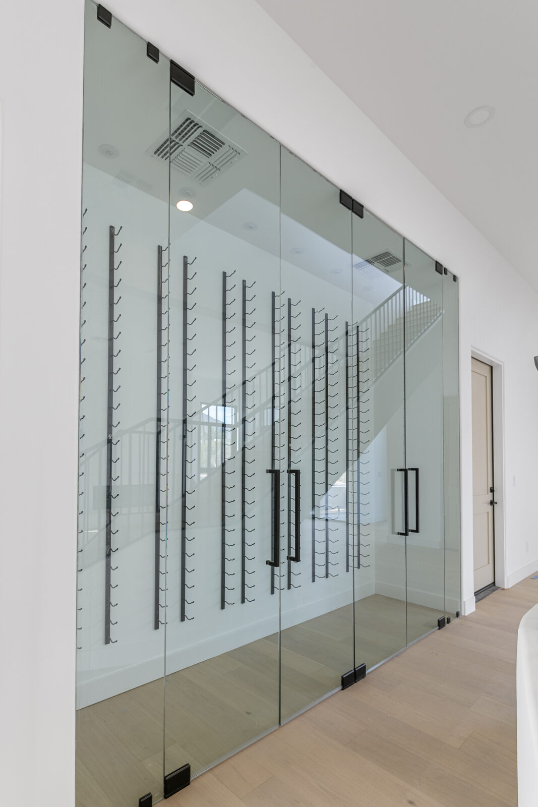 Frameless glass wine wall with metal racking and double glass doors