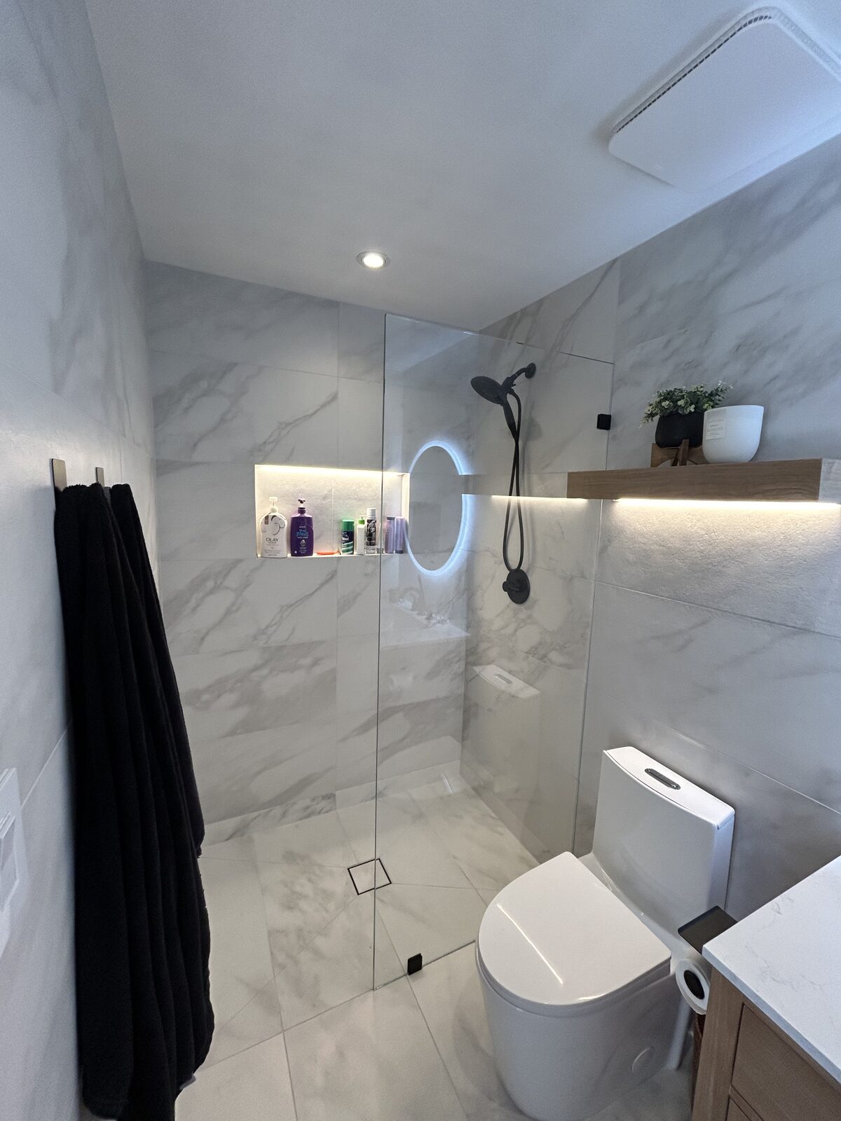 Marble walk-in shower with clear fixed glass panel and matte black fixtures
