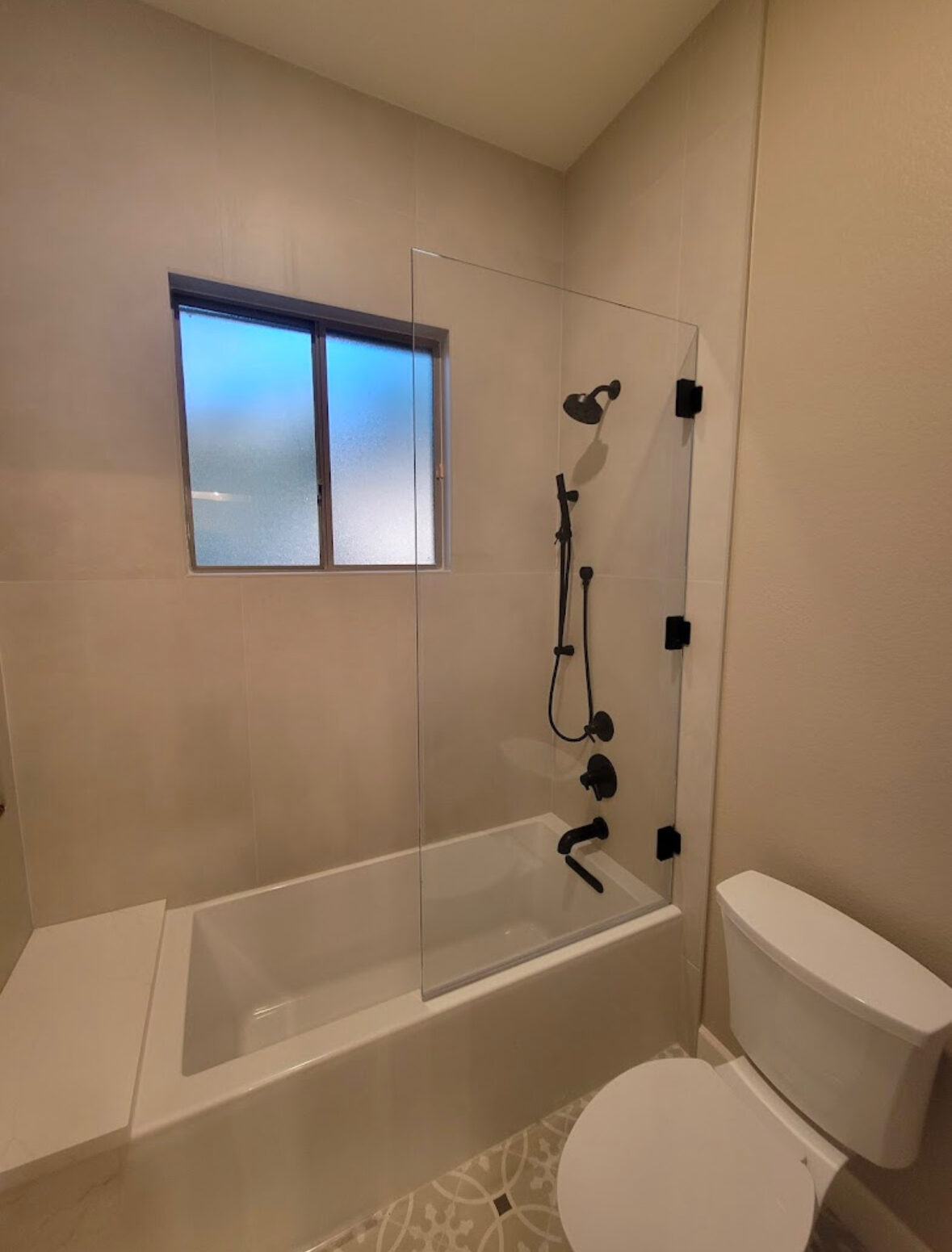 Tub and shower with single glass panel door and tiled window niche