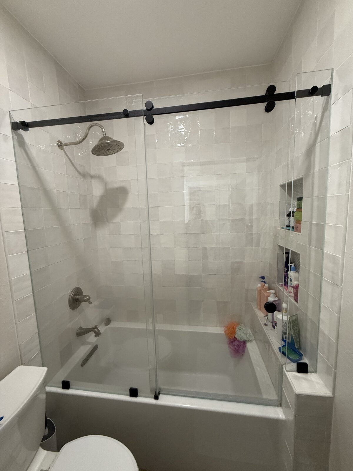 Gold barn style shower slider on a dark vertical tile enclosure