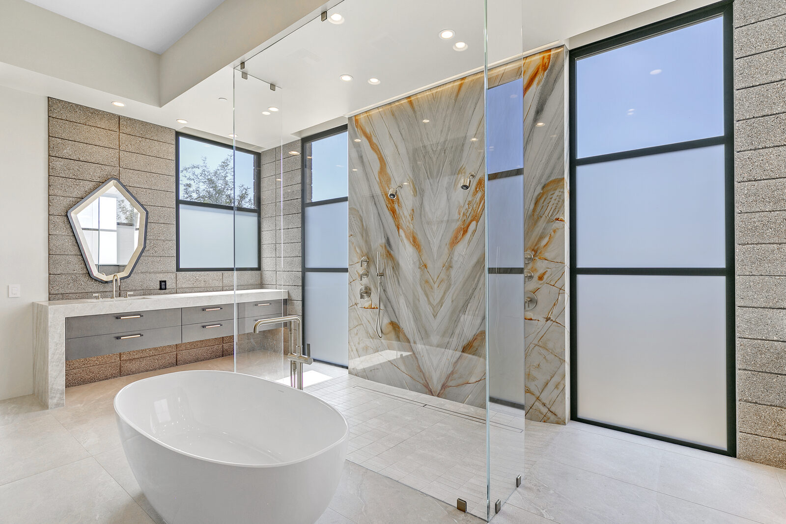 Walk-in shower with fixed glass panel, freestanding tub, and onyx feature wall