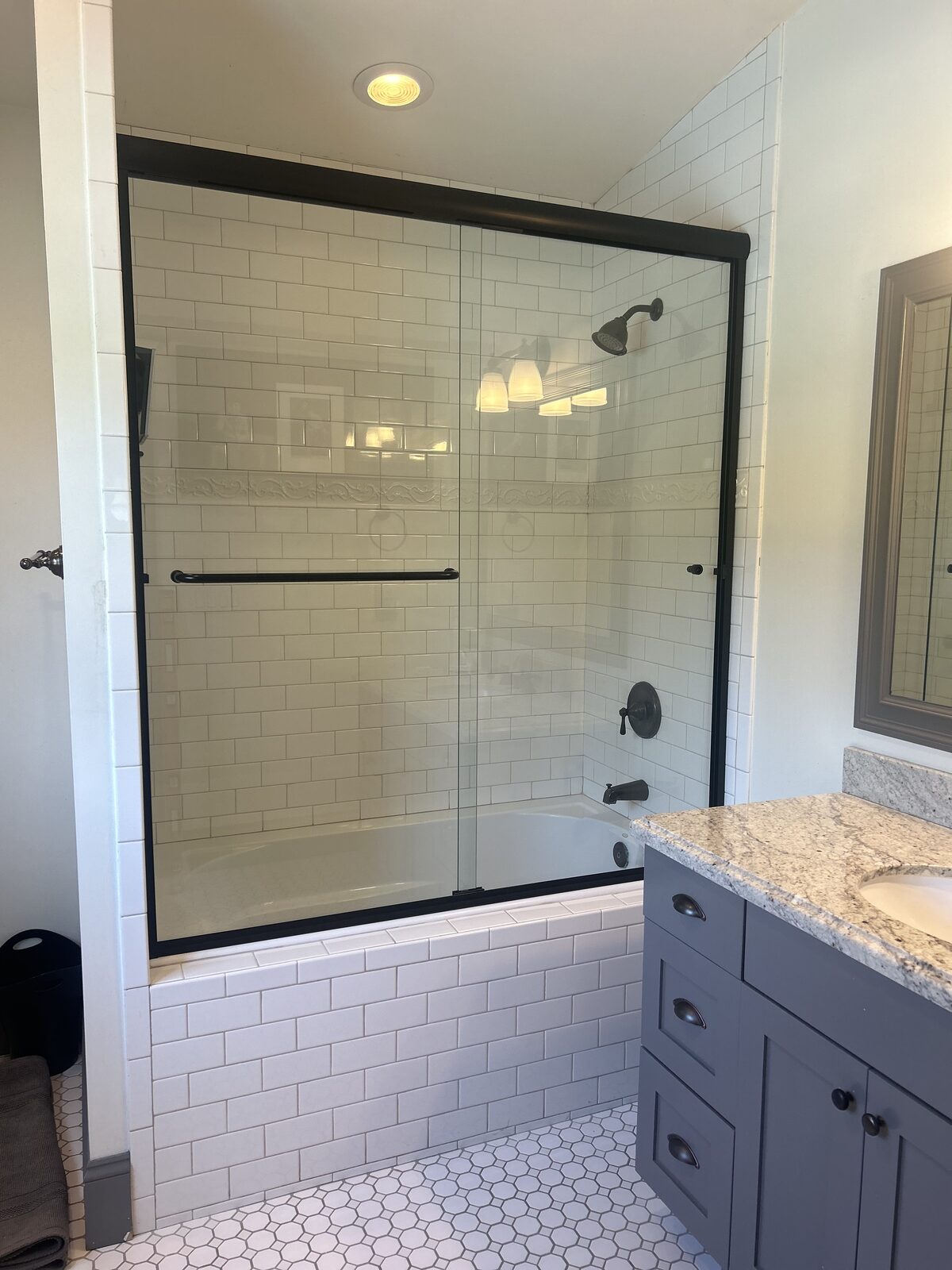 Matte black framed bypass doors on a subway tile tub surround