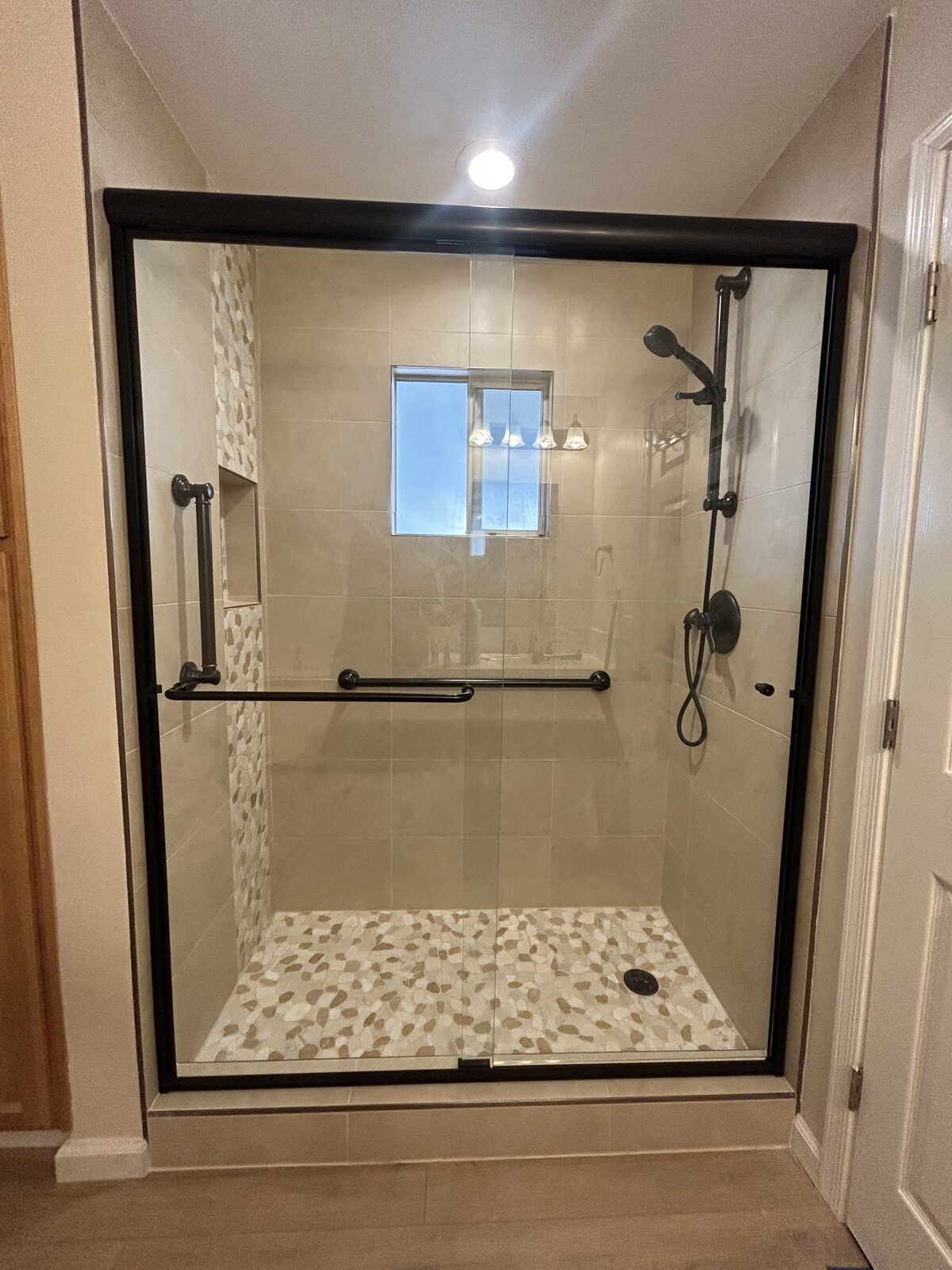 Black framed bypass shower doors with pebble shower floor