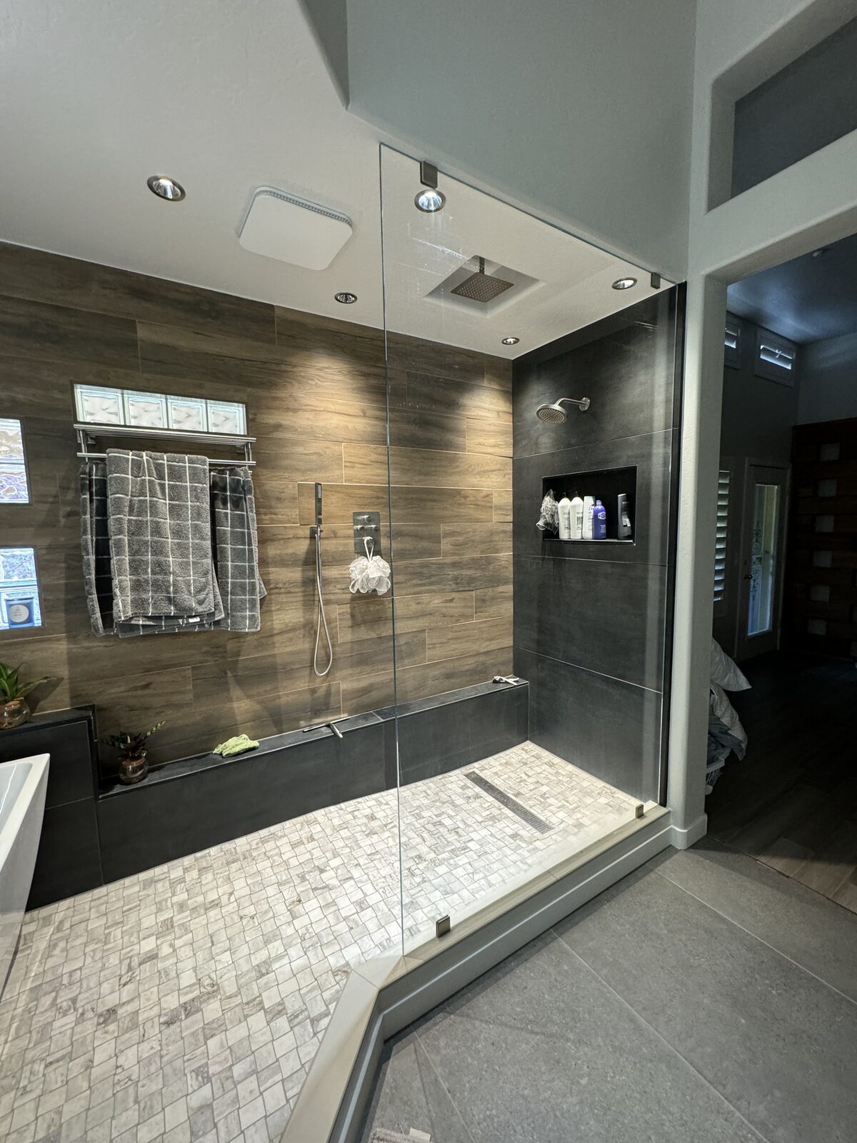 Dark wood look tile walk-in shower with clear fixed glass panel