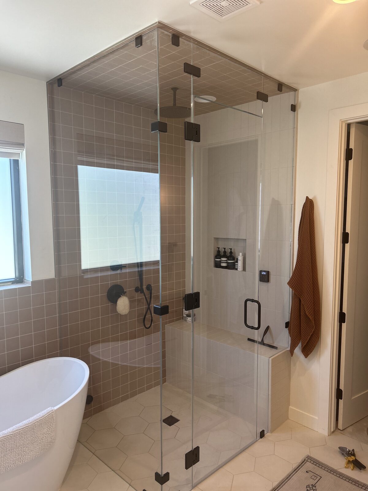 Corner steam shower enclosure with freestanding tub and tiled walls