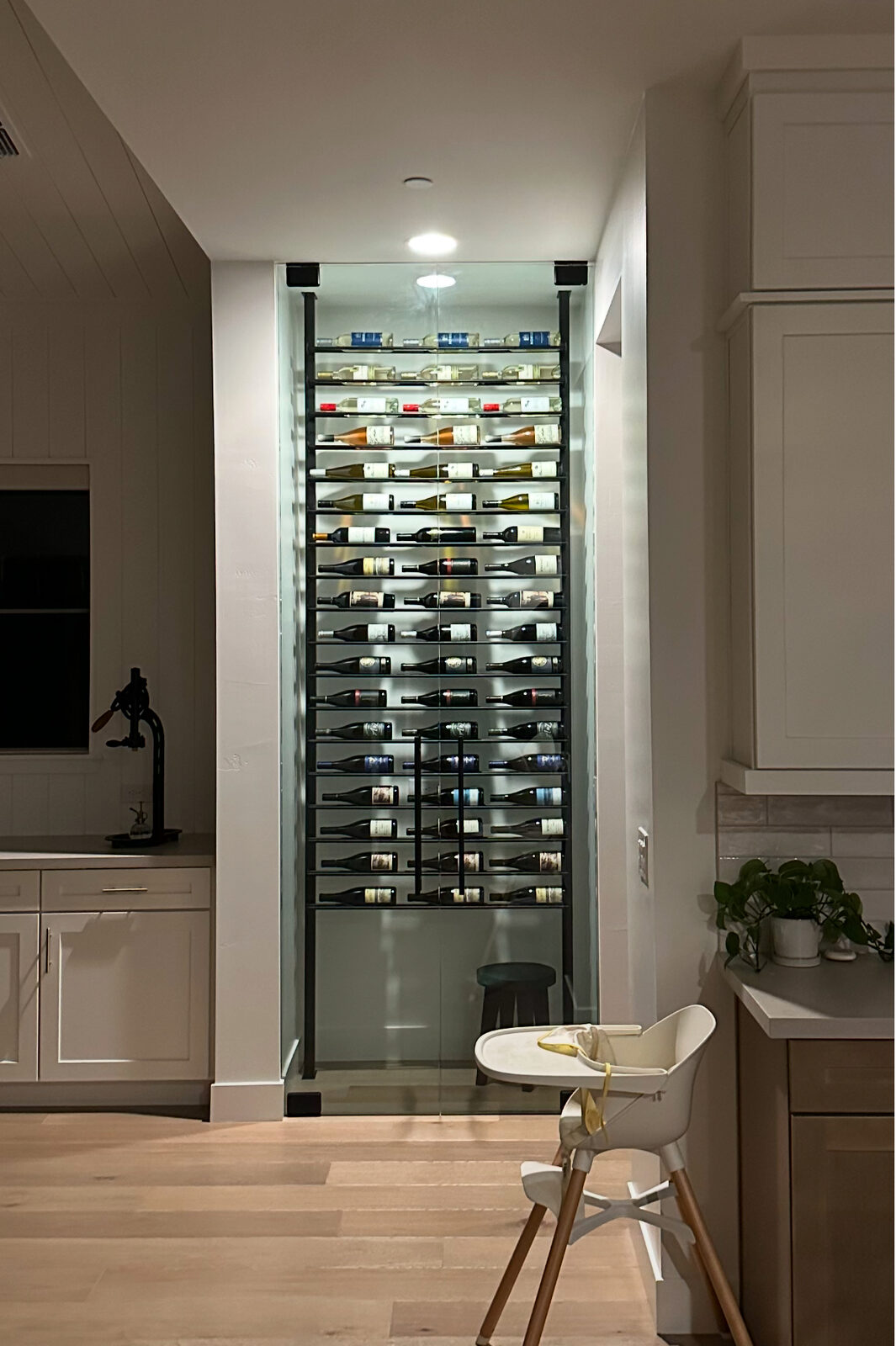 Illuminated glass wine wall built into a hallway