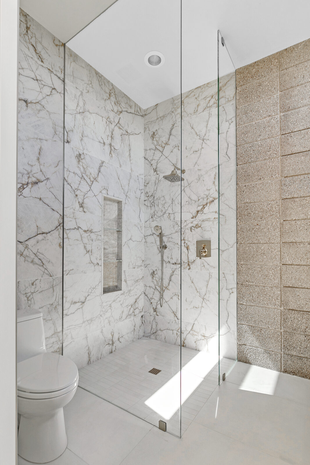 Marble walk-in shower with fixed glass panel and curbless entry